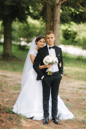 Newlyweds are walking in the park on the wedding day. Just married couple. Groom and bride on green backgroundの写真素材