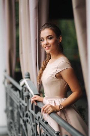 Elegant brunette lady stand on luxury balcony and smile. Fashion hairstyle and makeupの写真素材