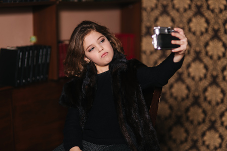 Little girl makes a photo on an old camera. Libraryの写真素材