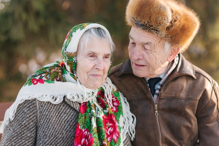 Senior people sits on the benck in the park. Happy elderly couple spend time outside in winterの写真素材