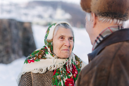 Elderly people look to each other in winter park. Romantic couple