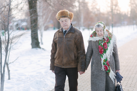 Romantic senior couple walkink in the park in winter time. Love forever. background of white winter snowの写真素材