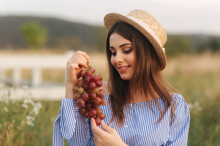 Beautiful pregnant woman show and eat red grapes. Healthy food. Fresh fruits. Happy woman smileの写真素材