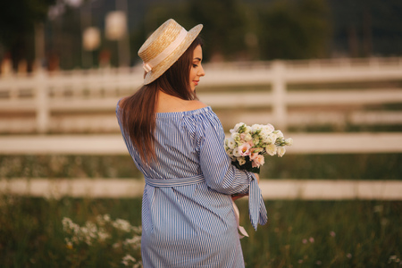 Back view of pregnant woman. She hold a bouquet of flowers and smileの写真素材