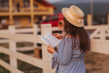 Beautiful pregnant woman read the book on the farm. She stand by the fance and look in to the book. Relaxの写真素材