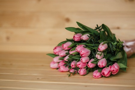 Bouquet of pink tulips with a beautiful bow on a wooden backgroundの写真素材