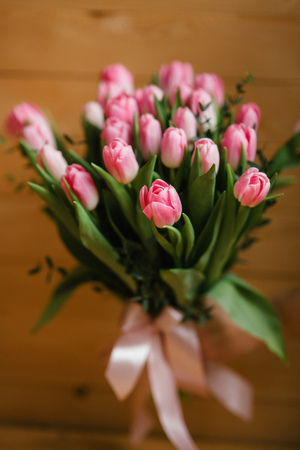 A bouquet of pink tulips in womans hands. Woden backgroundの写真素材
