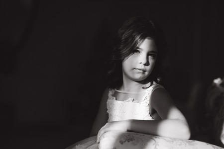 Sun rays fall on the face of little girl. Beautiful little model in studio with natural lightの写真素材