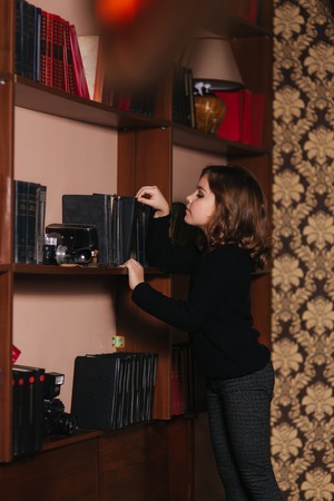Beautiful little girl is reading a book in the library. Preparing for a schoolの写真素材