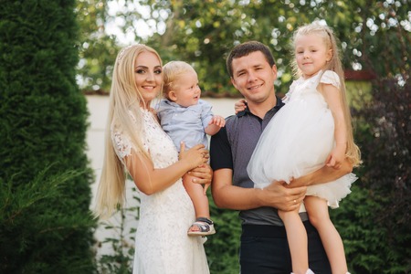 Mom, dad, son and daughter is big family. They love each other and walk though the parkの写真素材