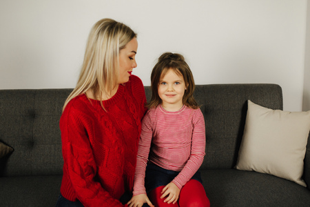 Mom and daughter play at home. Little girl tickle her mother. Happy family spend time together. Blond hair womanの写真素材