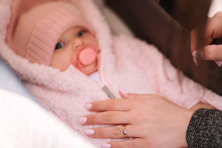 Little baby girl in stroller. Mom put her hand on babyの写真素材