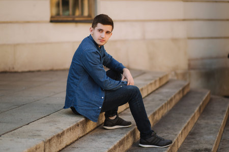 Handsome man sitiing on the stairs near the park