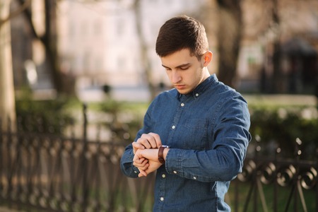 Handsome business man look at the watch in the city. Man ajust the exact time on the watchの写真素材