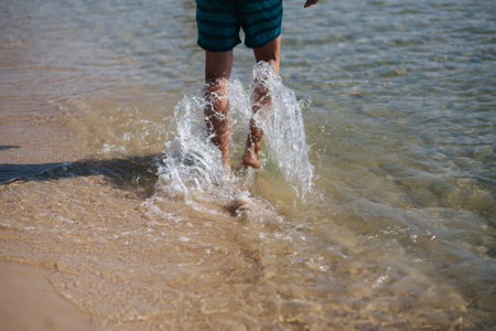 Back view of man bare foot walking on the summer beach. Close up leg of man walking in the sea,...