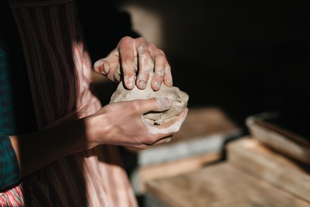 Close up of man works with clay. Male potter kneads and moistens the clay before work, tonedの写真素材