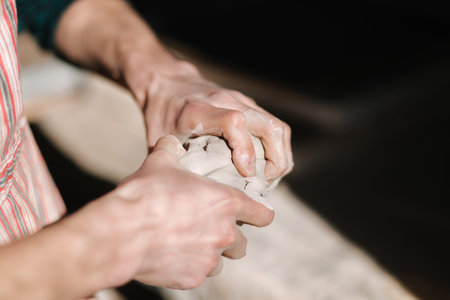 Close up of man works with clay. Male potter kneads and moistens the clay before work, toned