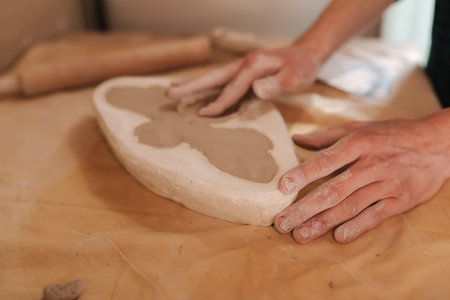 Hands of a potter creating element of decor using a clay. Close up of male hands