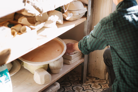 Man potter looking for ware for a work. Young man potter in his workshop. Handsome man workの写真素材