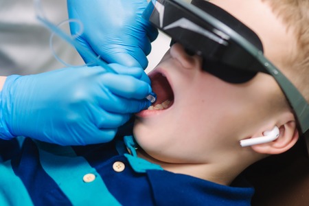 Close up of little boy sitting in dentist in vr glasses and wireless headphones while dentist make x-ray of teethの写真素材