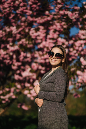 Bussines woman in blazer and sunglasses stand in front of pink treeの写真素材