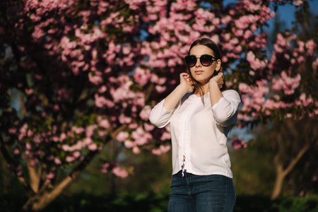 Attractive woman in white shirt in the park. Background of pink tree