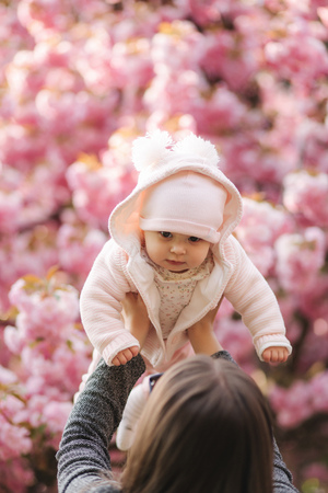 Happy young mother holding baby girl in her hands and looking at her with loveの写真素材