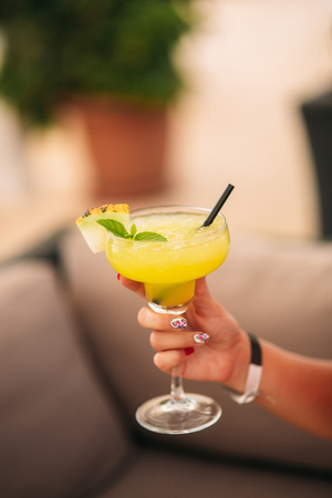 Coctail in womans hand on the beach. Yellow coctail with melonの写真素材