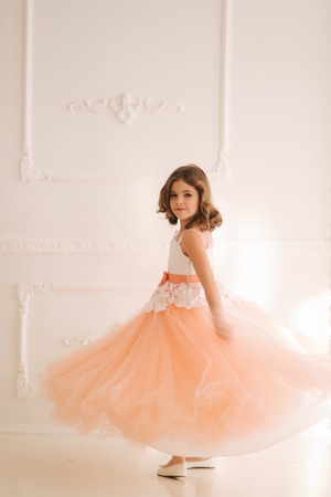 Happy little princess in beautiful dress walk though the big studio. spin aroundの写真素材