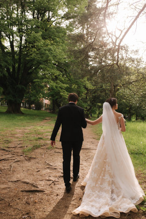 Back view of broom and bride walking in the forest