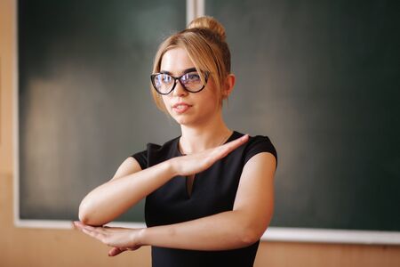 Young female teacher in glasses stand in front of blackboardの写真素材