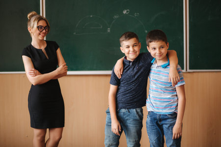 Teacher help boys by the blackboard. Young female teacher studyの写真素材