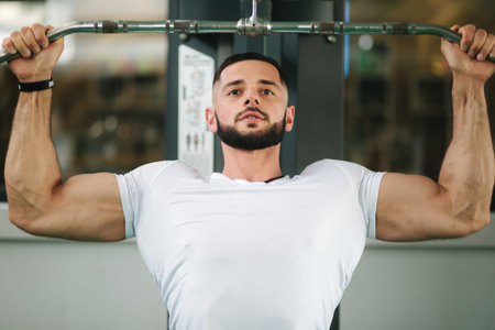 A young athlete trains in the gym. Shows the muscles of the back and chest