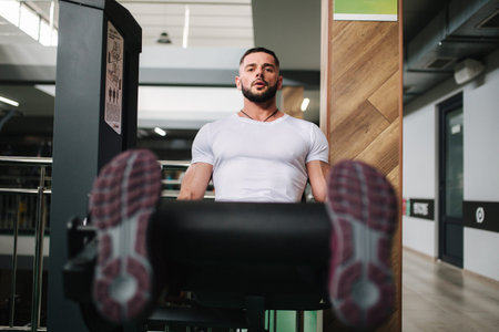 Man trains legs in gym. Handsome bearded bodybuilder training