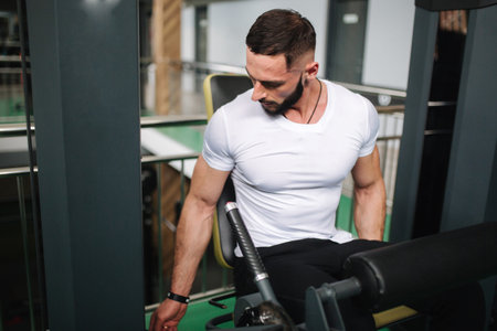 Man trains legs in gym. Handsome bearded bodybuilder training