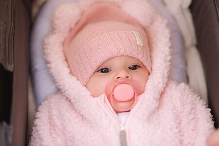 Little baby girl in stroller. Mom put her hand on babyの写真素材