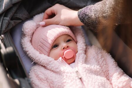 Little baby girl in stroller. Mom put her hand on babyの写真素材