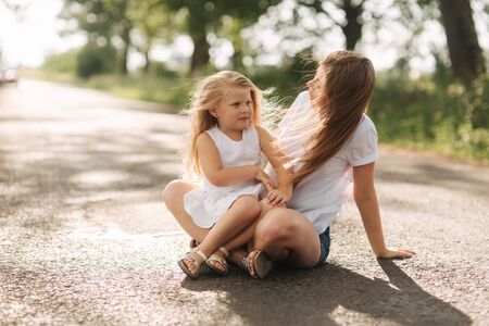 Happy loving family. Mother and her daughter child girl playing and hugging. alley of big trees. close up viewの写真素材