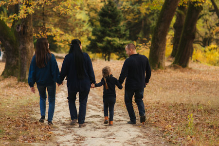 Happy family walking in the park. Mom dad and two daughter. Back view