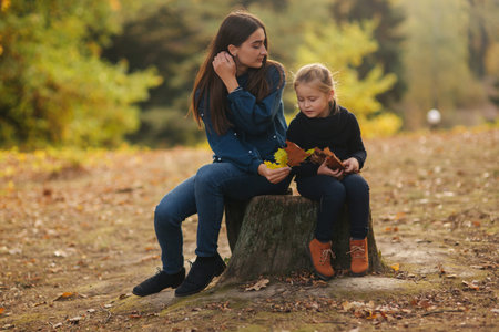 Two happy sisters walking in the park in the autumn. Little sister with teenage sister