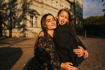 Two happy sisters walking in the park in the autumn. Little sister with teenage sister