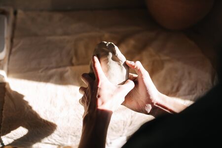 Close up of man works with clay. Male potter kneads and moistens the clay before work, tonedの写真素材