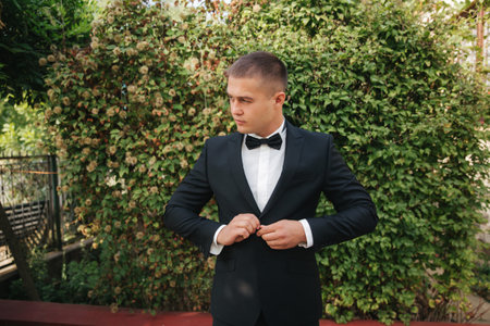 Young man walking in the park. Handsome groom in black suit