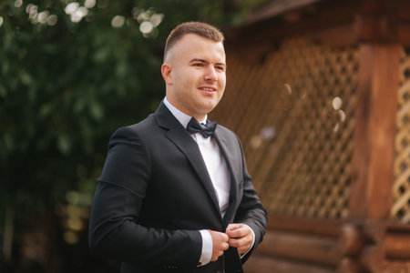 Morning of handsome groom outside. Wedding day. Background of green tree. Summer timeの写真素材