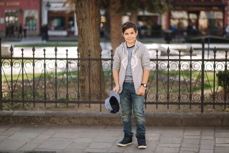 Stylish little school boy in blue cap posing outside for photo. Boy walking in the city in sping summer weatherの写真素材