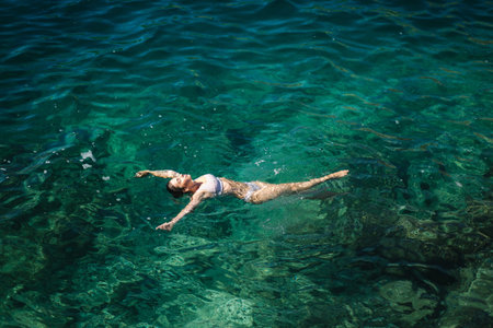 Sexy woman in bikini lying on the water. Attractive young woman enjoying summer sun. Beautiful...