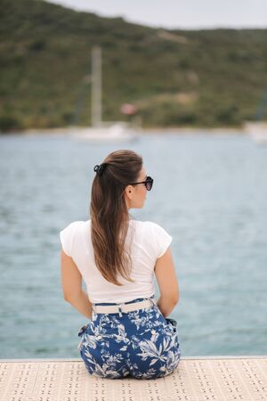 Back view of woman sit on the pier by the sea. Beautiful seaの写真素材