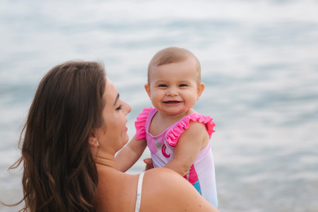 Mom kiss her little daughter on the beach. Backgound of sea