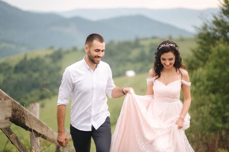 Beautiful young wedding couple standing on the green slope, hill. Groom and bride in Carpathian mountainsの写真素材