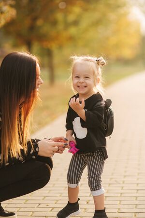 Mother and little daughter walking in autumn weather. Stylish little daughter and her beautiful mother. Happy childhood. Outdoors portrait of happy family. Have funの写真素材